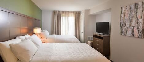 A hotel room with two beds, a TV, a dresser, and a painting on the wall.
