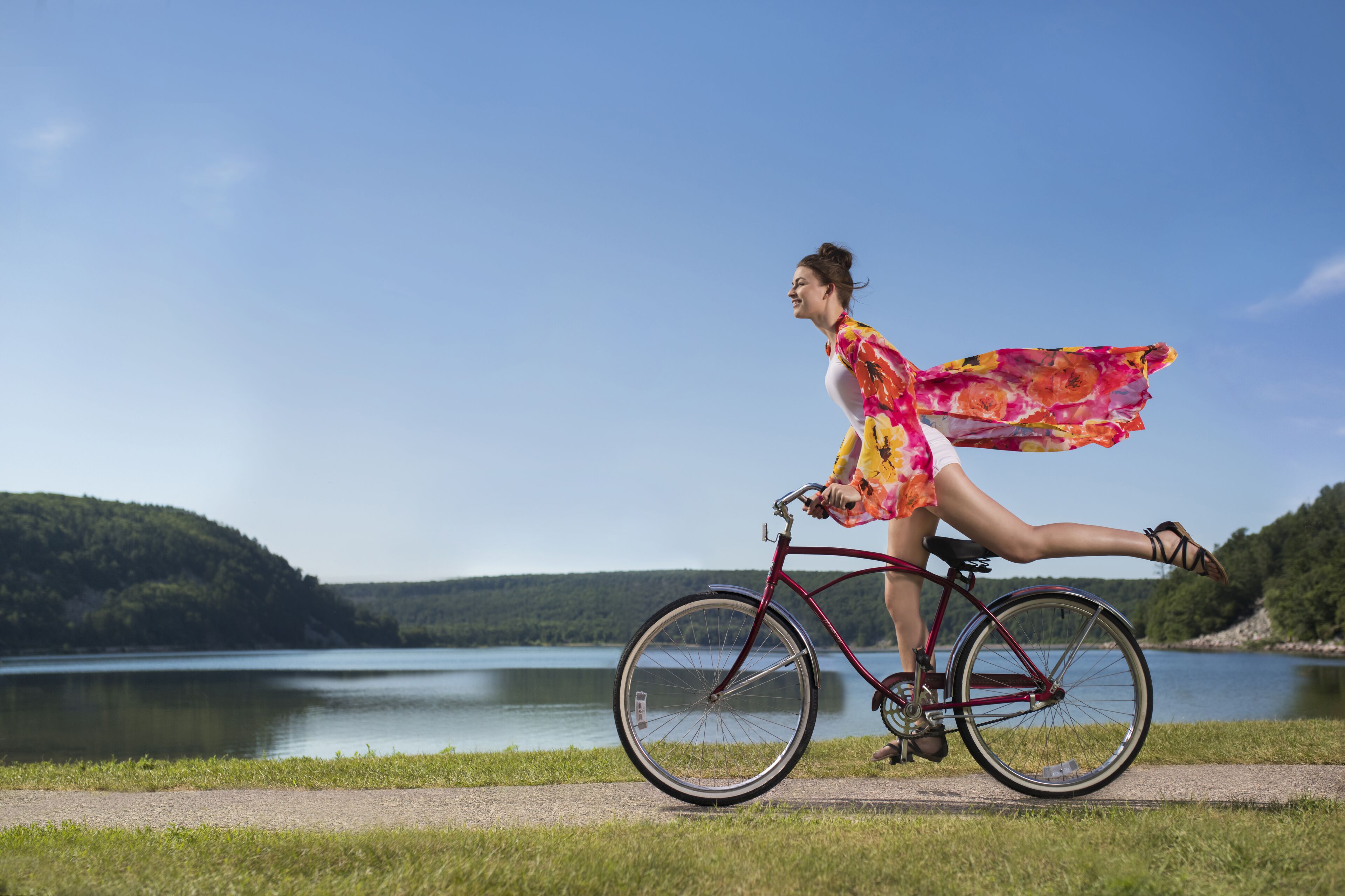 A woman riding a bicycle on a path by a lake.