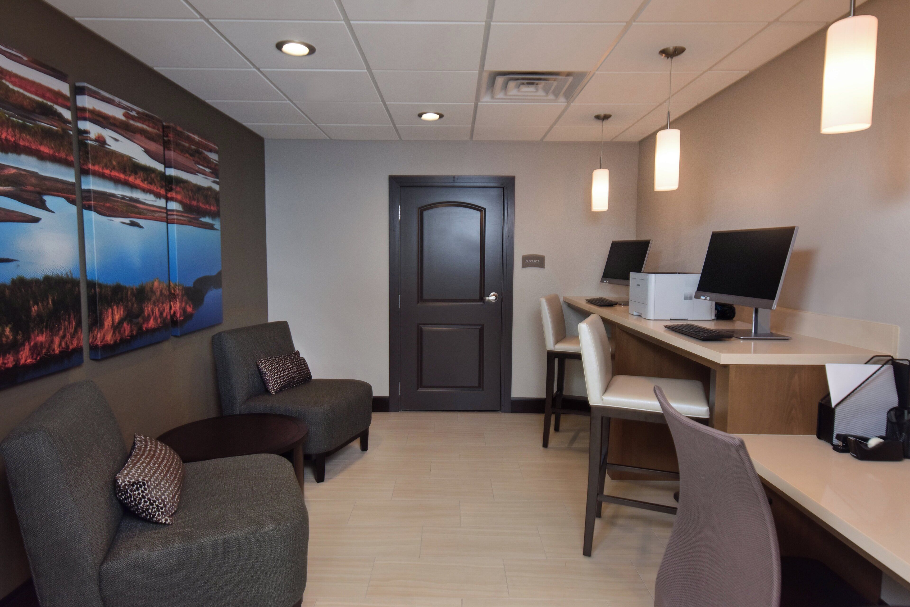 A reception area with a desk, computer, chairs, and a door.
