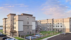 A multi-story hotel with a stone facade, a basketball court, and a parking lot. - Staybridge Suites Wisconsin Dells - Lake Delton by IHG (Wisconsin Dells)