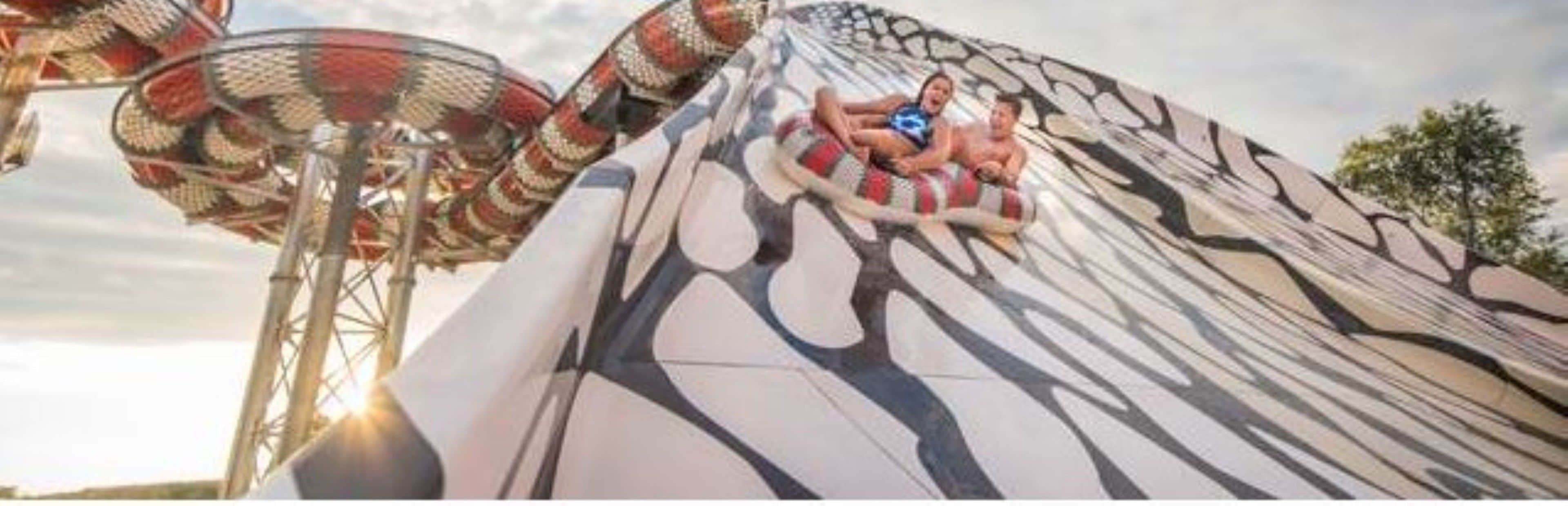 A water slide with a large, curved structure and a person sitting on a tube.