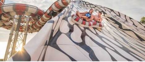 A water slide with a large, curved structure and a person sitting on a tube.