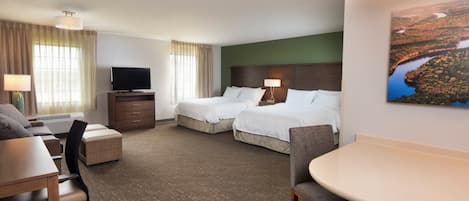 A hotel room with two beds, a desk, a chair, a TV, and a painting on the wall.