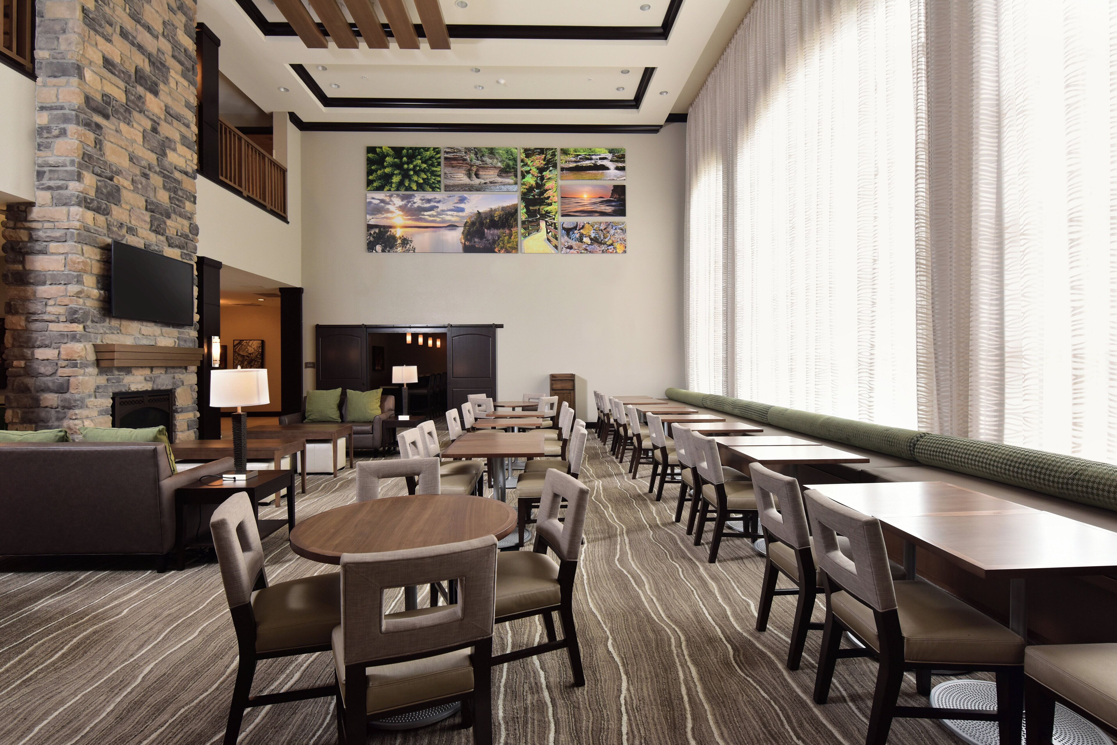 A hotel lobby with a fireplace, seating area, and a long dining table with chairs.