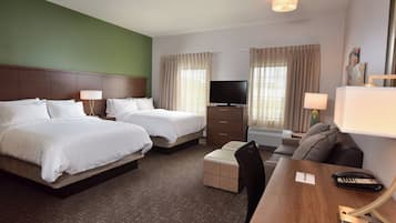 A hotel room with two beds, a desk with a telephone, a television, and a chair.