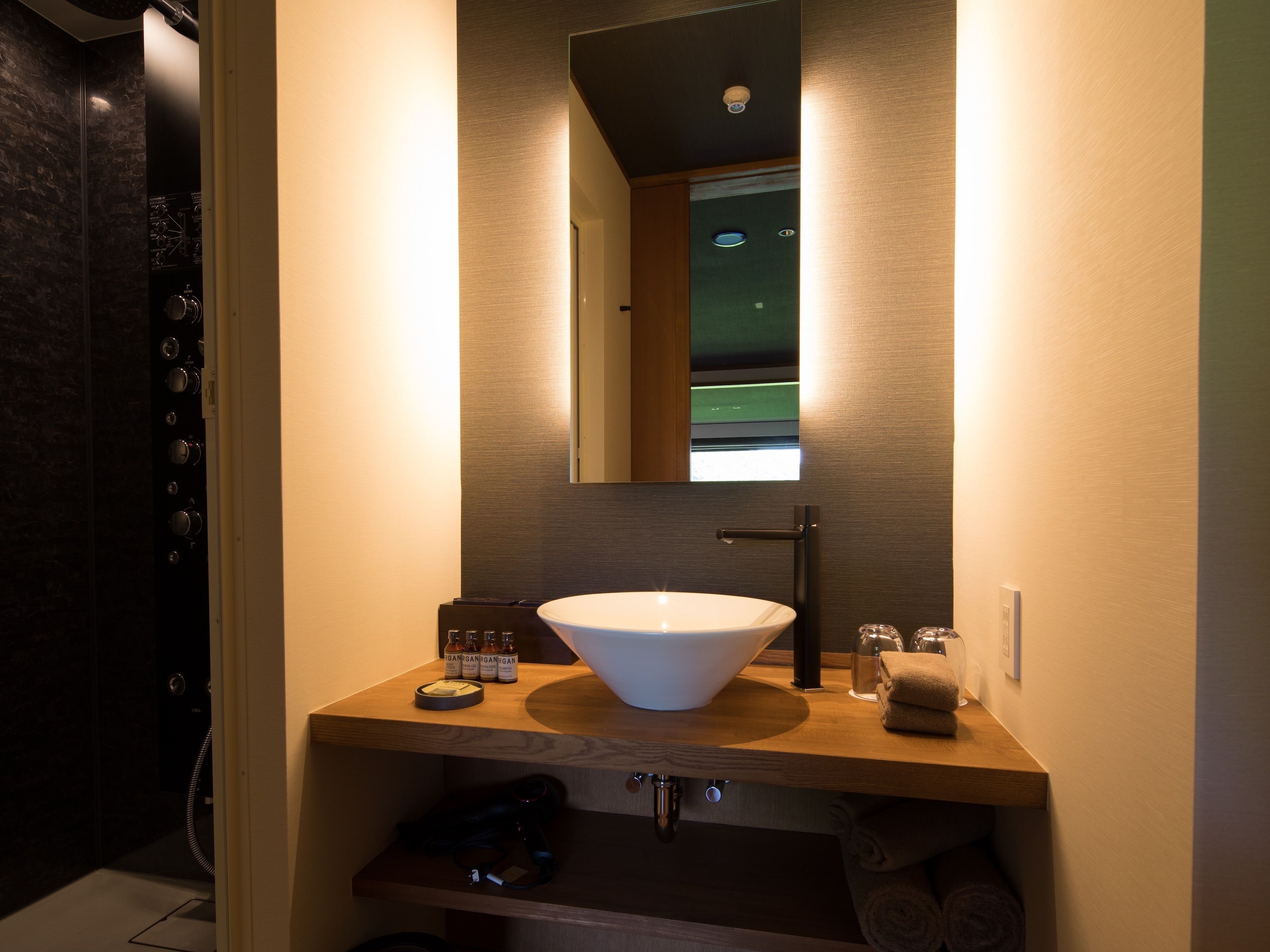 Ein modernes Badezimmer mit einem großzügigen Waschtisch, einem Spiegel und einer Holzausstattung.