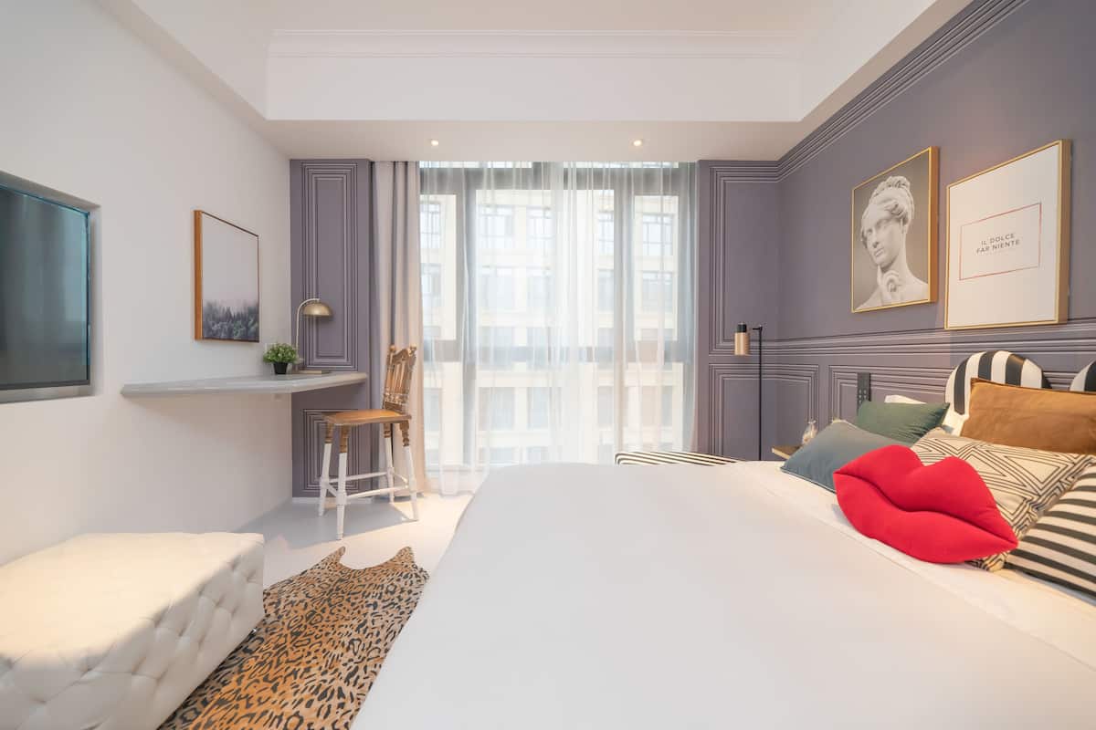 A modern bedroom with a large bed, a desk, and a chair.