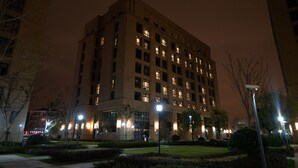 A multi-story building with illuminated windows at night, surrounded by landscaped gardens and street lamps. - Zhongjian Rui Beiting hotel apartment (Shanghai)