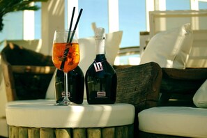 A glass of rosé wine with a straw and a bottle of rosé wine on a table.