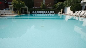 A clear swimming pool with white lounge chairs arranged around it. - Hotel Major (Cervia)