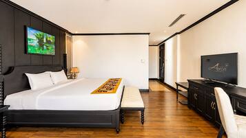 A hotel room with a large bed, a desk, a TV, and a painting on the wall.