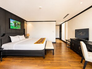 Habitación de hotel con una cama grande, un escritorio, un televisor y un cuadro en la pared.