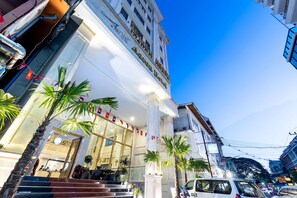 Fachada imponente de un hotel, con columnas grandes y palmeras.
