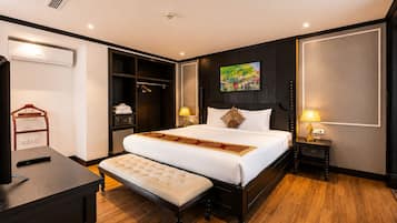 Una habitación de hotel con una cama grande, mesitas de noche, un armario y un escritorio con un control remoto.