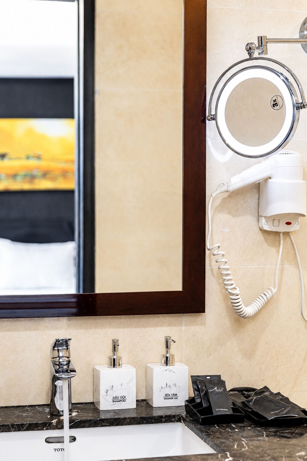 Un baño con espejo, secador de pelo y dos botellas de champú y gel de ducha.