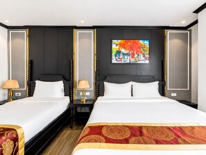 Habitación de hotel con dos camas, un cuadro grande en la pared y un cabecero decorativo.