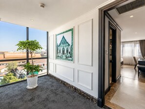 A hotel room with a large window, a potted plant, a framed picture, and a view of the cityscape. - Aaron Vientiane Hotel (Vientiane)