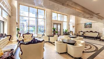 A spacious lobby with high ceilings, large windows, and classic furniture.