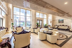 Un vestíbulo amplio con techos altos, ventanas grandes y muebles clásicos.