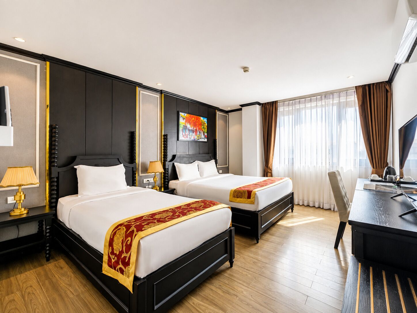 A hotel room with two beds, a desk, a chair, a television, and a painting on the wall.