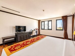 A hotel room with a large bed, a TV, a desk, and a window with curtains. - Aaron Vientiane Hotel (Vientiane)