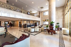 Un vestíbulo amplio con mostrador de recepción, zona de estar y barandilla decorativa.