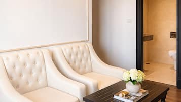 A modern living room with a tufted sofa, a dark wooden coffee table, and a view into a bathroom.