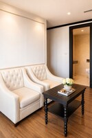 A modern living room with a tufted sofa, a dark wooden coffee table, and a view into a bathroom.