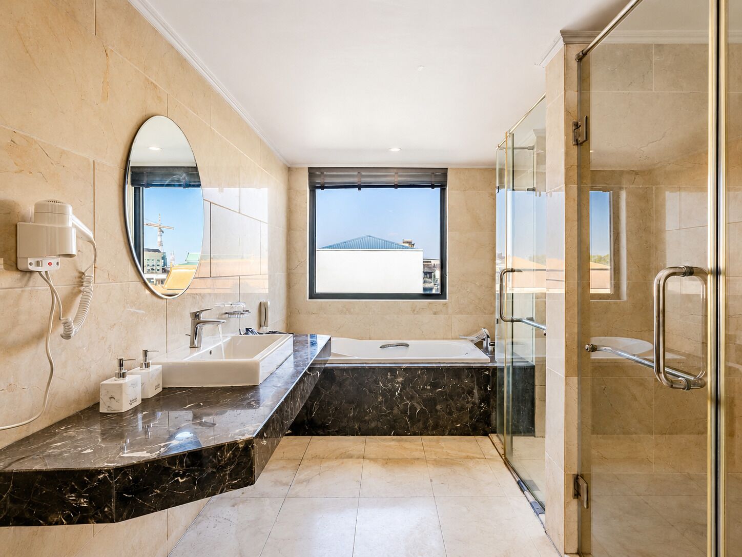 A modern bathroom with a large mirror, a window, a shower, and a vanity.