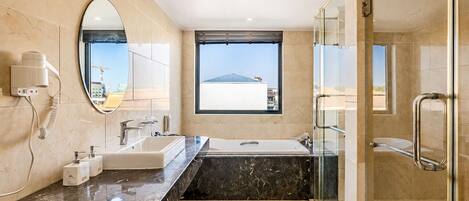 A modern bathroom with a large mirror, a window, a shower, and a vanity.