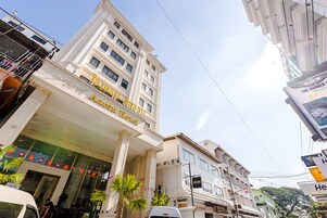 Un hotel con una entrada destacada, varios pisos y cielo despejado.