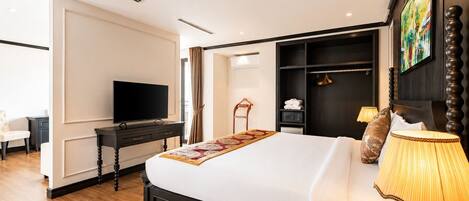 Habitación de hotel con cama, escritorio con televisor, armario y un cuadro en la pared.