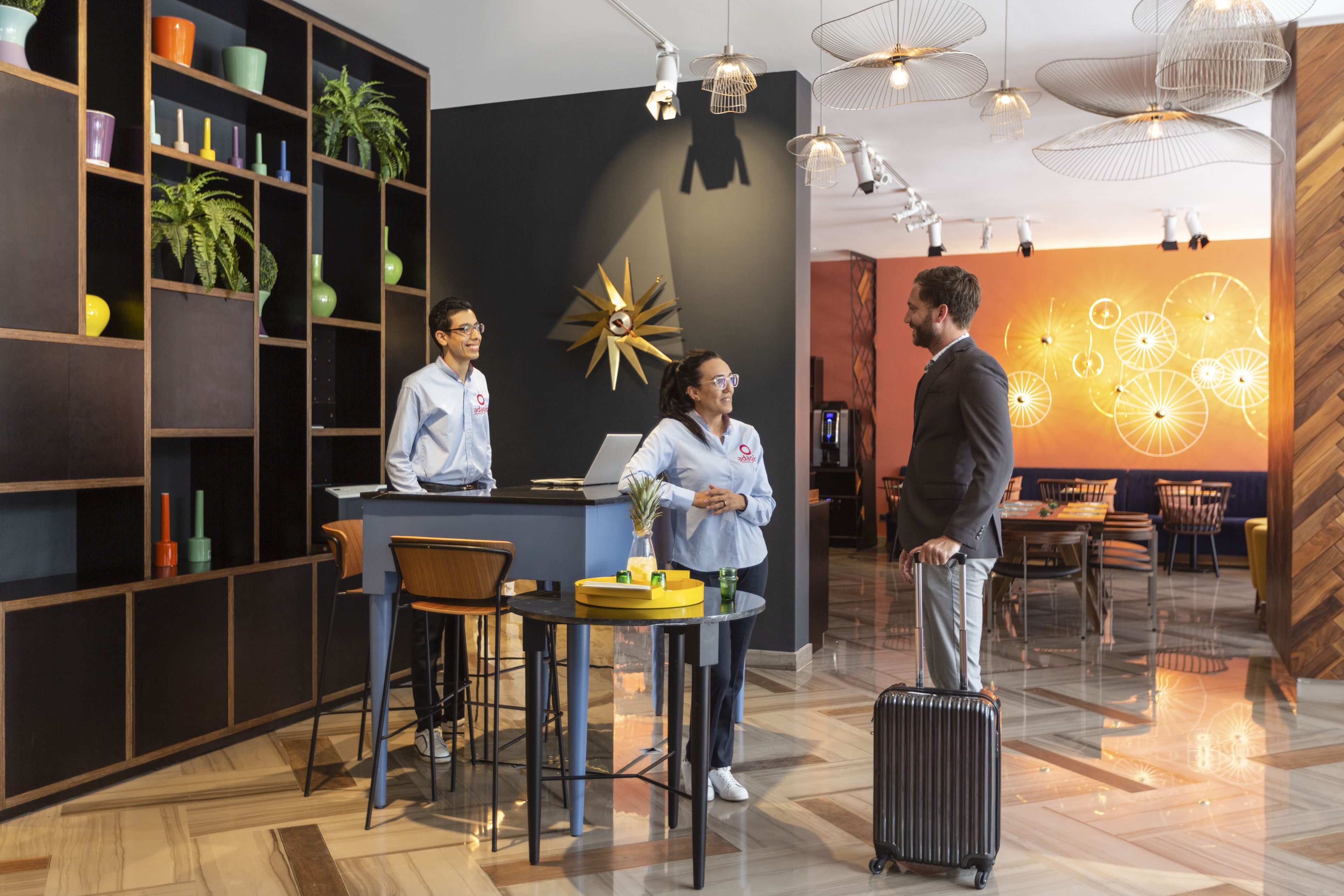 A modern hotel lobby with a reception desk, seating area, and decorative wall art.