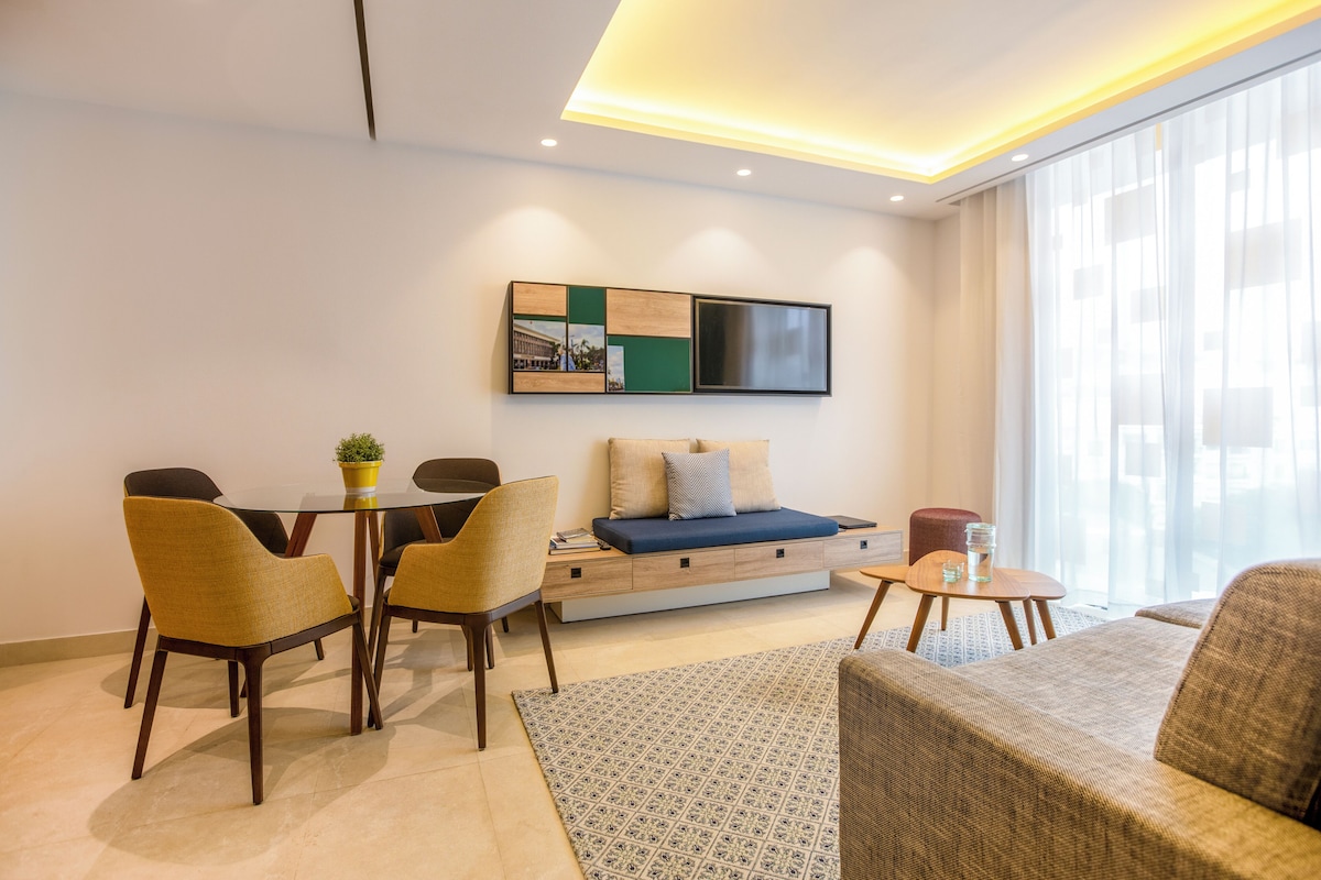 A modern living room with a sofa, chairs, a coffee table, and a TV mounted on the wall.