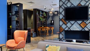 Una sala de estar moderna con un sofá, un sillón estampado color naranja y un televisor montado en la pared.