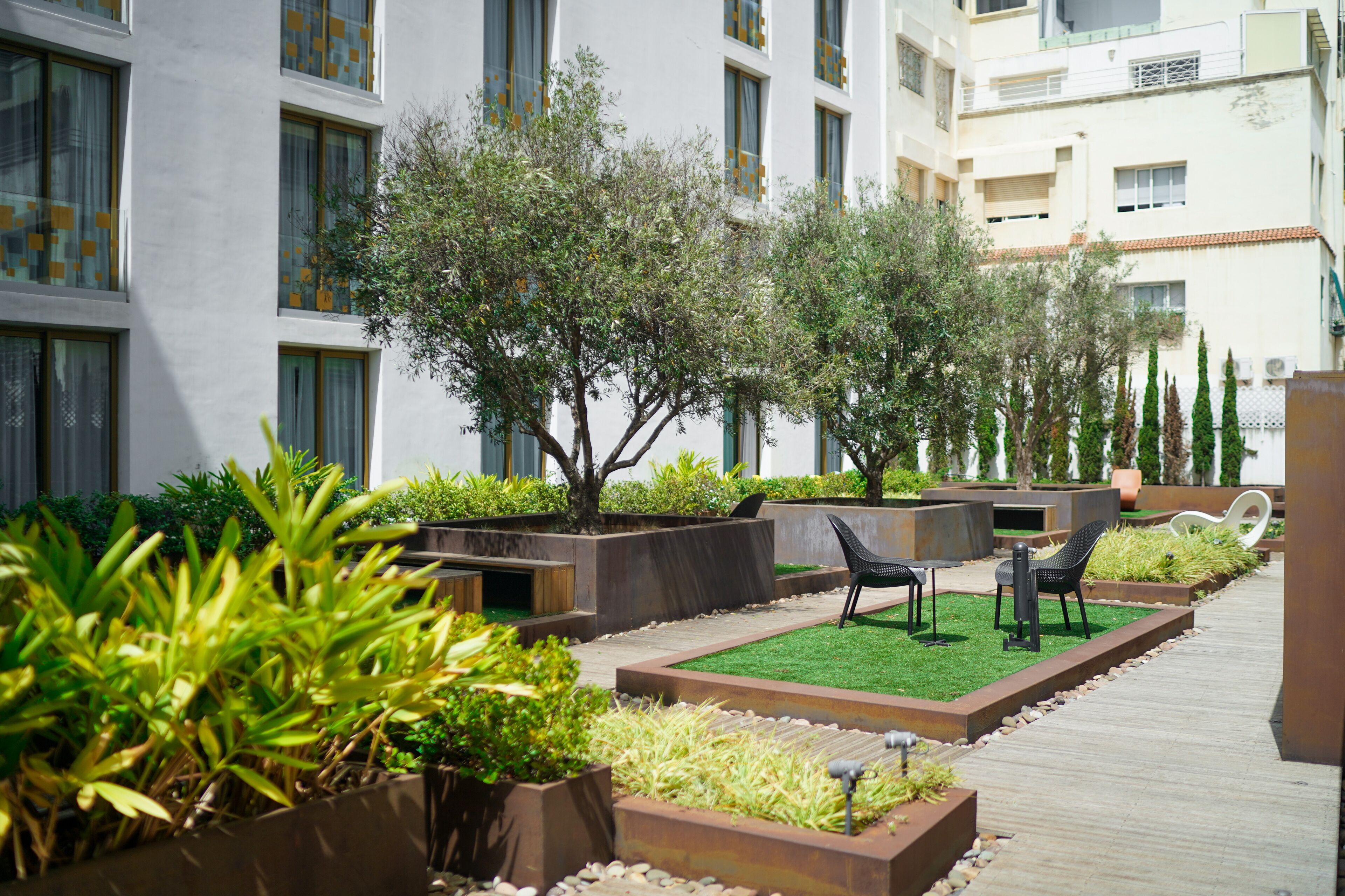 A modern outdoor area with planters, seating, and a pathway.