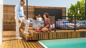 Zona junto a la piscina con cubierta de madera, sillas de descanso y pileta.
