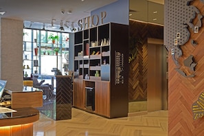A modern interior with a reception desk, a 'SHOP' sign, and a herringbone-patterned wall.