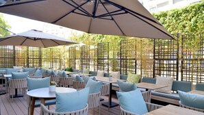 An outdoor seating area with tables and chairs, covered by large umbrellas, and surrounded by a bamboo fence. - Aparthotel Adagio Premium Casablanca City Center (Casablanca)