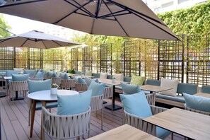 An outdoor seating area with tables and chairs, covered by large umbrellas, and surrounded by a bamboo fence. - Aparthotel Adagio Premium Casablanca City Center (Casablanca)
