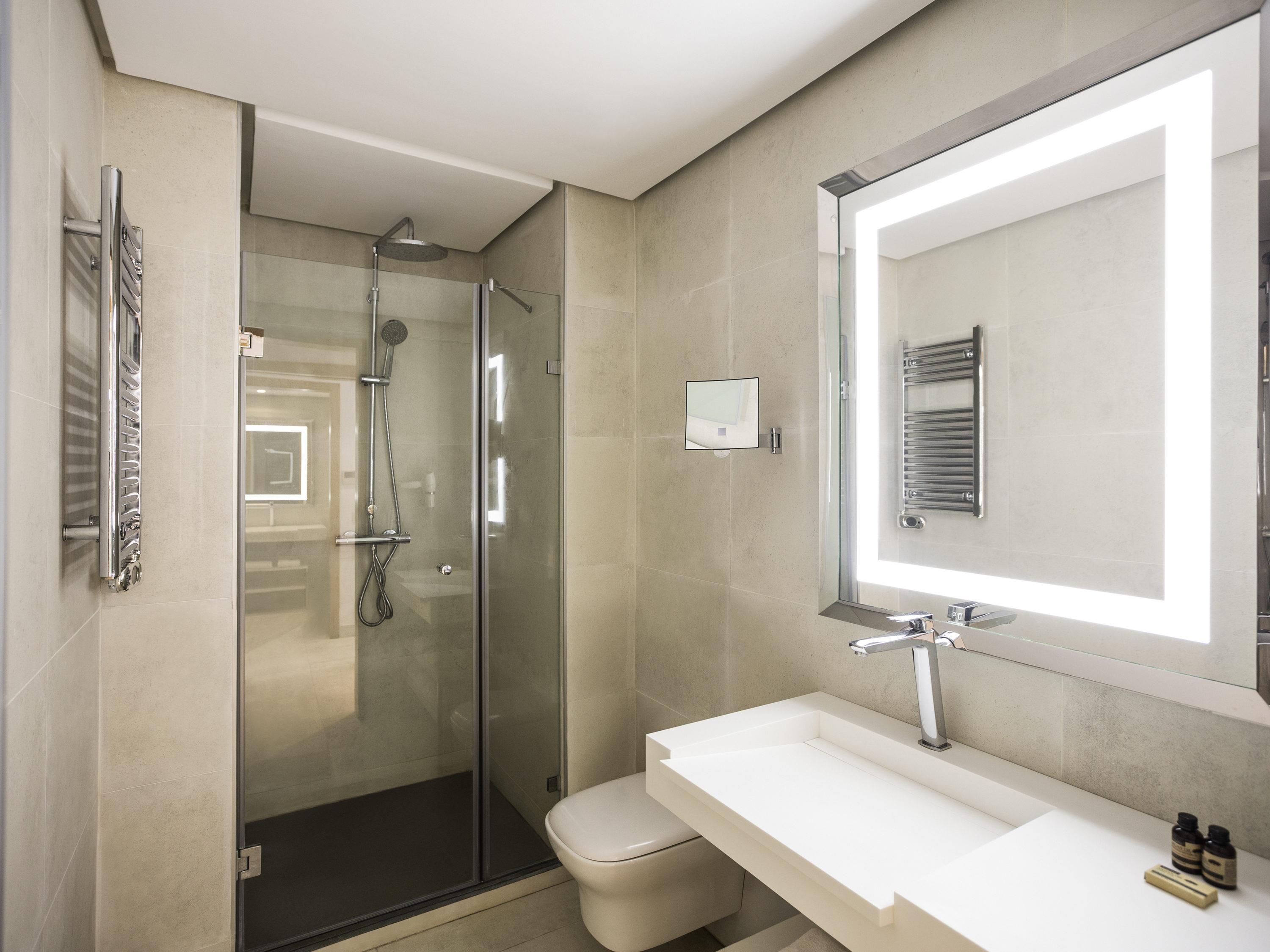 A modern bathroom with a glass-enclosed shower, a white sink, and a large mirror.