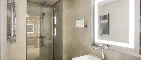 A modern bathroom with a glass-enclosed shower, a white sink, and a large mirror.