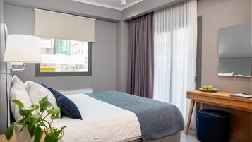 Una habitación de hotel moderna con cama, escritorio, lámpara y ventana con cortinas.