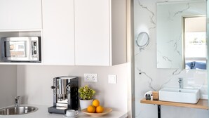 A modern kitchen with a built-in espresso machine, a sink, and a marble backsplash. - Chroma Fashion Rooms & Apartments (Chalandri)