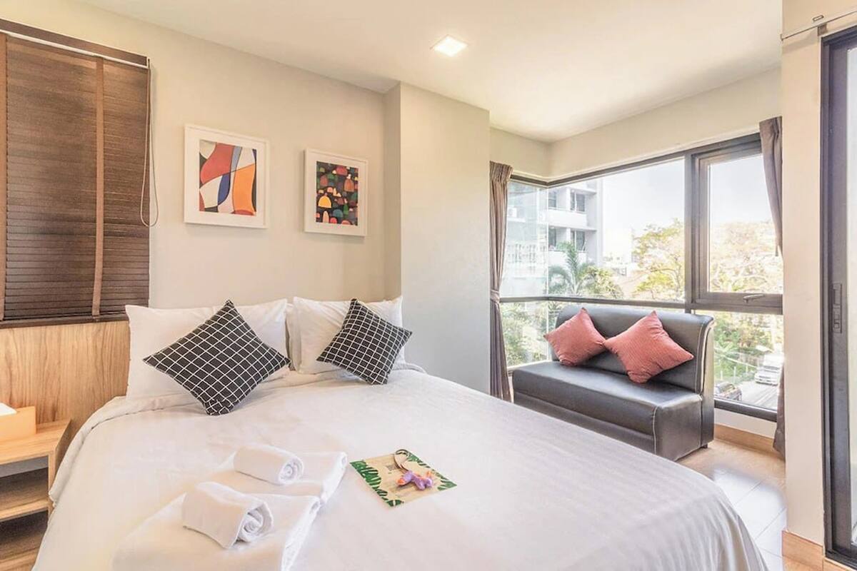 Una habitación de hotel con una cama grande, un sofá y una ventana que ofrece vistas a edificios.