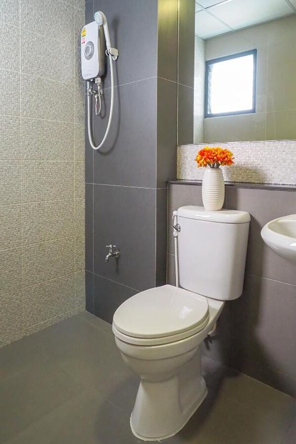 A modern bathroom with a toilet, a shower unit, and a sink. - Casaluxe Hotel Ratchada (Bangkok)