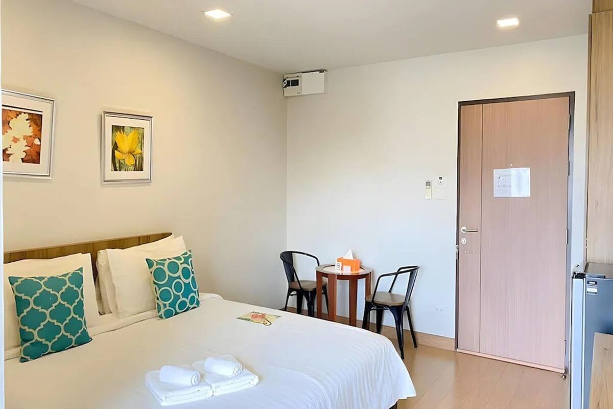 Una habitación de hotel con una cama, dos sillas, una mesita y una puerta.