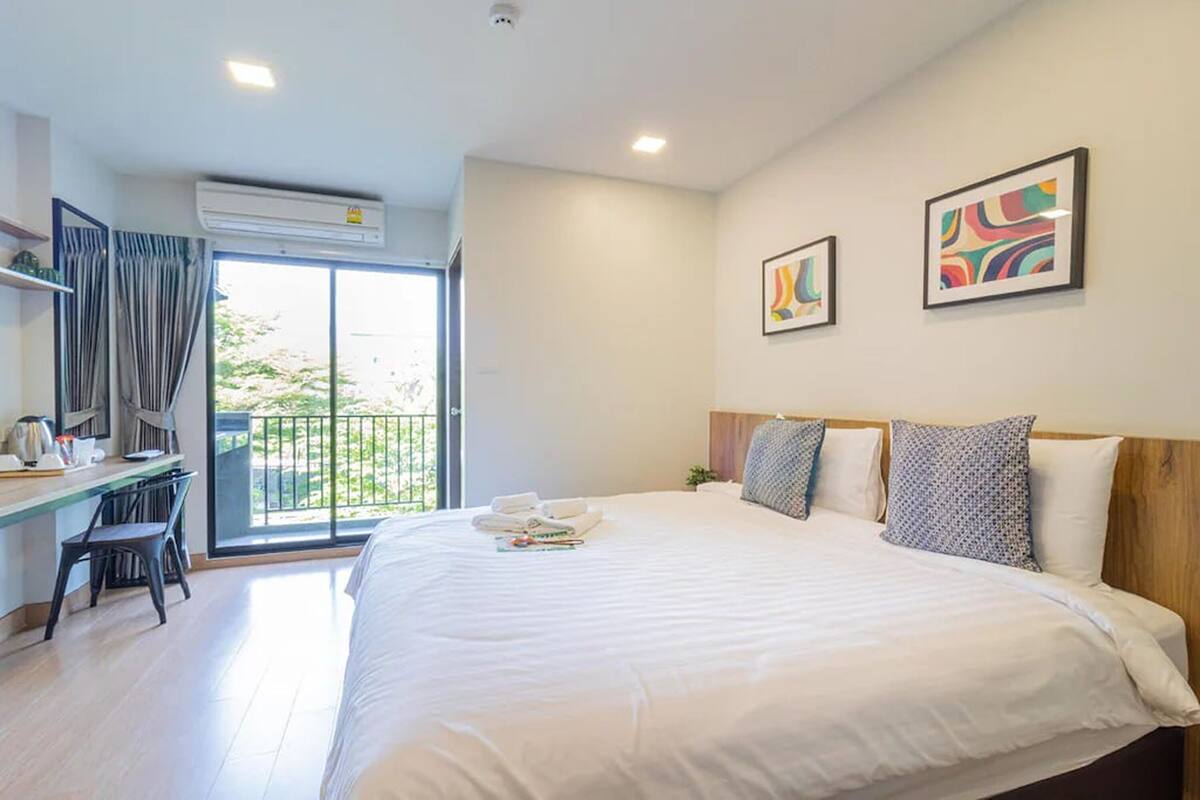 Una habitación de hotel con una cama grande, un escritorio con silla y un balcón con cortinas.