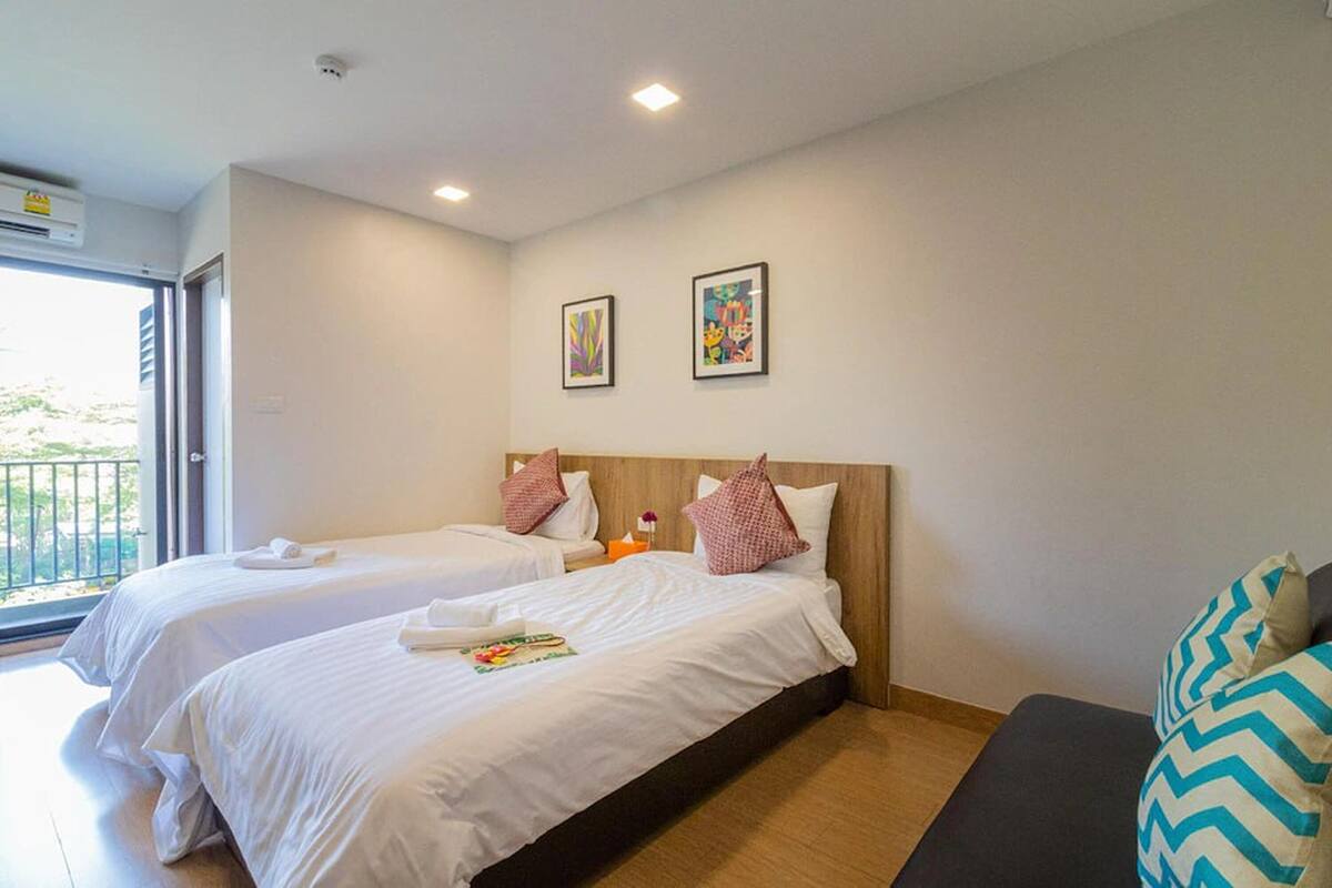 Habitación de hotel con dos camas, un sofá y obras de arte en la pared.