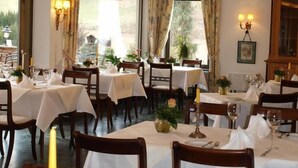 A dining area with multiple tables set for guests, featuring wooden chairs and white tablecloths. - Der Watzenhof (Hemsbach)